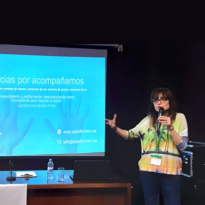 Mujer hablando con un micrófono delante de una pantalla de proyecciones