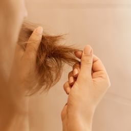 Manos de mujer sosteniendo un mechón de pelo dañado
