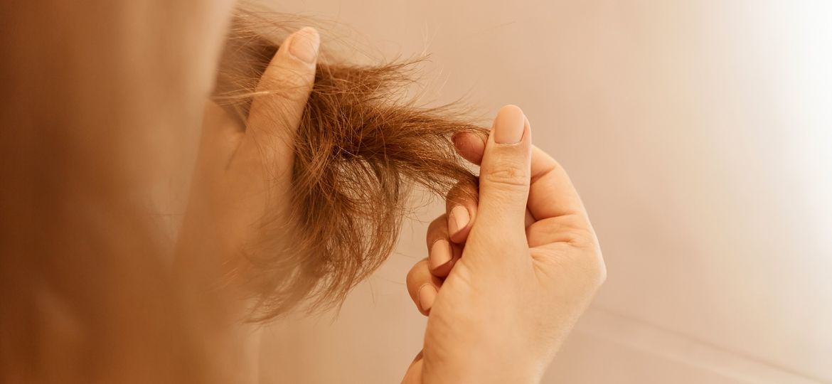 Manos de mujer sosteniendo un mechón de pelo dañado