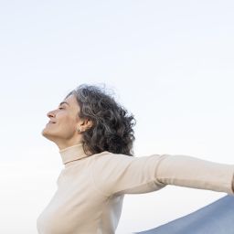 Mujer de mediana edad con los brazos abiertos y sonriendo