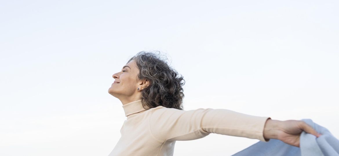Mujer de mediana edad con los brazos abiertos y sonriendo
