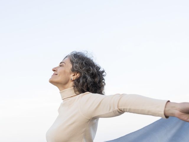 Mujer de mediana edad con los brazos abiertos y sonriendo